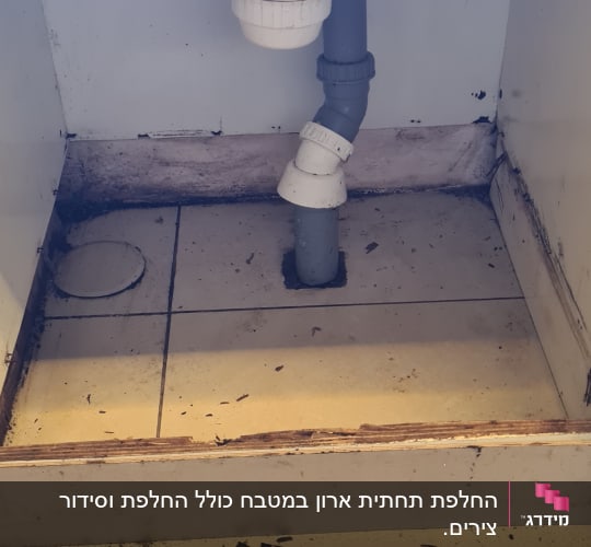 צנרת מתחת לכיור עם לכלוך על הרצפה